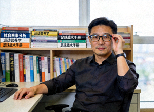 爱游戏体育官网首席内容官王健先生半身工作照，身后书架摆满体育类书籍